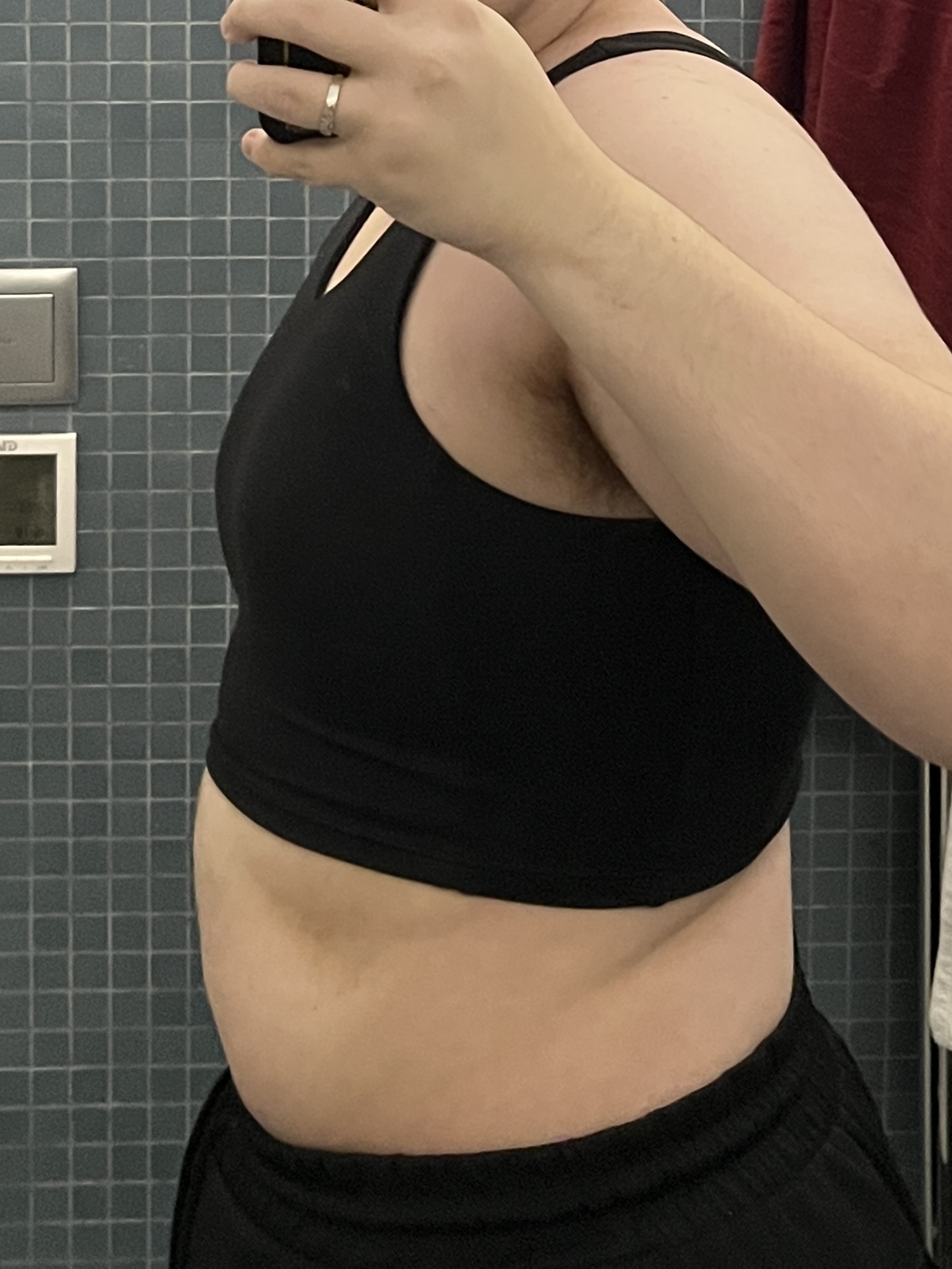 Trans man wearing a black half binder facing sideways